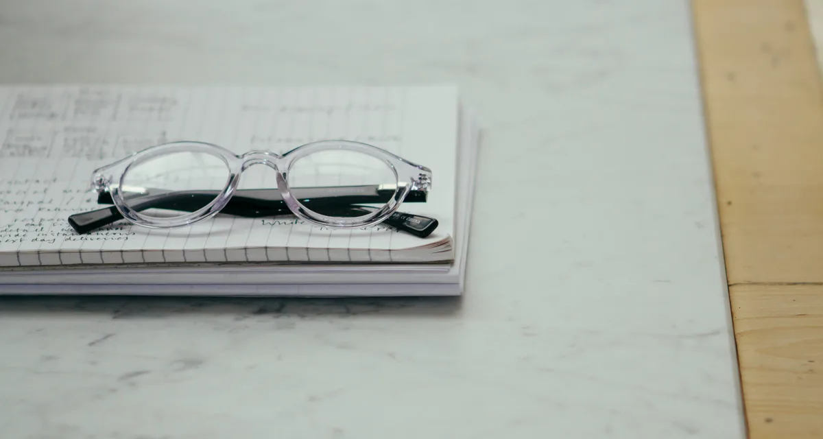 Glasses resting on an open notebook on a desk